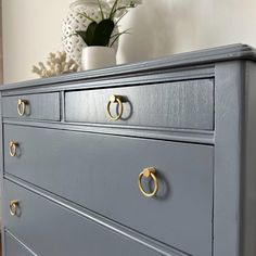 a gray dresser with brass handles and knobs