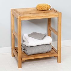 a wooden shelf with folded towels and a bowl on the top, against a white wall