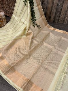 -Classic cream Kanjivaram saree with a striped zari pattern and heavy zari palla. -Pure silk saree authenticated by Silk Mark Certificate. -Blouse fabric included. -Fall attached. Note:  - Slight inconsistency in weaving is inherent to handloom sarees and is not a defect. -The color of the products may slightly vary according to the ambient lighting conditions and the color calibration of LED devices. If you would like more clarity before your purchase, please drop us a message . Gold Art Silk Pre-draped Saree With Border, Gold Slub Silk Pre-draped Saree For Festivals, Bollywood Style Gold Pre-draped Saree With Border, Cream Pre-draped Saree With Cutdana For Diwali, Cream Cutdana Pre-draped Saree For Diwali, Cream Pre-draped Saree With Zari Work For Diwali, Off White Tissue Silk Traditional Wear For Diwali, Diwali Cream Pre-draped Saree With Zari Work, Diwali Off-white Tissue Silk Traditional Wear