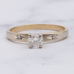 an engagement ring with a diamond in the center on a marble tableclothed surface