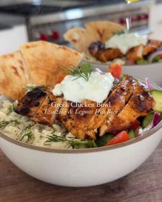 a bowl filled with chicken and rice next to pita bread