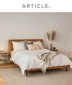 a bed with white linens and pillows in a bedroom next to a lamp on the floor