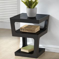 a vase with flowers on top of a black shelf next to a book and a stack of books