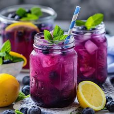 two mason jars filled with blueberry lemonade and mint garnish on a table