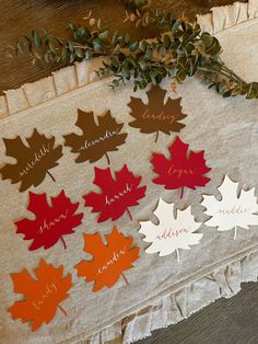 a bunch of leaves that are on top of a cloth tablecloth with name tags attached to them