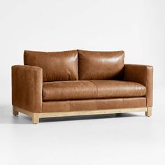 a brown leather couch sitting on top of a white floor next to a wooden frame