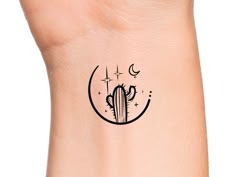 a small cactus and moon tattoo on the side of a woman's arm,