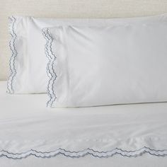 two white pillows with scalloped edges on a bed