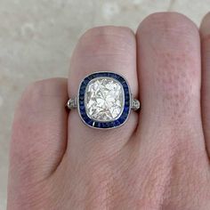 a woman's hand with a diamond and blue sapphire ring