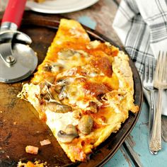 a slice of mushroom and cheese pizza on a plate next to a knife and fork