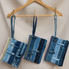 two small purses hanging on a wooden hanger next to a white cloth covered wall