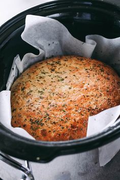 a cooked meat in a crock pot with some napkins on the side,