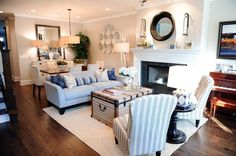 a living room filled with furniture and a fire place under a mirror on the wall