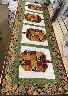 a quilted table runner with elephants on it in the middle of a store aisle