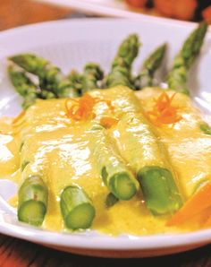 a white plate topped with asparagus covered in cheese