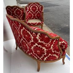 a red and white couch sitting on top of a sidewalk