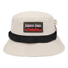 Step into the world of Jurassic Park fashion with this striking white bucket hat. A black band wraps around, setting the stage for the woven label that proudly displays the iconic movie title against a backdrop of vibrant red jungle foliage. But this hat isn't just about style – it's designed with functionality in mind. The fleece-lined side pocket adds a practical touch, making it easy to carry your essentials while embracing the adventurous spirit of the franchise. Crafted from high-quality po Jurassic Park Logo, Jungle Foliage, White Bucket Hat, White Caps, Woven Label, Iconic Movies, Cap Design, Jurassic Park, Side Pocket