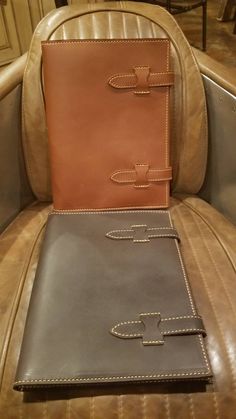 a brown and black leather book sitting on top of a chair