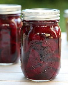 two jars filled with pickles sitting on top of a table