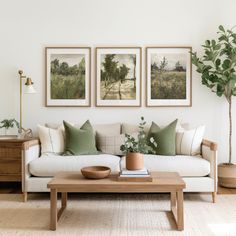 a living room with three paintings on the wall and a coffee table in front of it