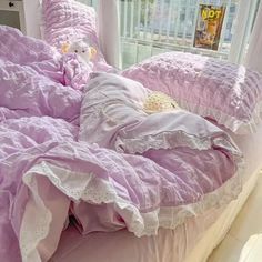 an unmade bed with pink comforter and white ruffled bedspread in front of a window