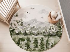 a round rug with trees and mountains painted on the floor next to a crib