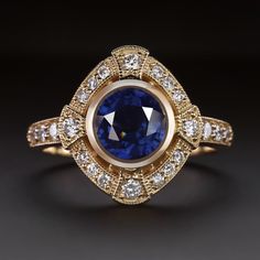 Why we love it: This sapphire and diamond cocktail ring features a rich blue sapphire circled by a glittering halo of diamonds! The Art Deco style details add a touch of vintage glamour and sophistication! Highlights: - 1.75ct natural sapphire center with beautiful rich blue color - 0.37ct of high quality accent diamonds - Romantic vintage style details - Classic 14k yellow gold setting Dimensions: 6.1mm across (north-south) and 5.0mm from the finger to the top of the ring. An appraisal is avail Halo Art, Art Deco Sapphire Ring, Beautiful Baubles, Vintage Cocktail Ring, Diamond Cocktail Ring, Round Sapphire, Sapphire Color, Art Deco Stil, Diamond Cocktail Rings