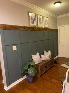 a living room with wood floors and green paneling on the walls, along with a plant