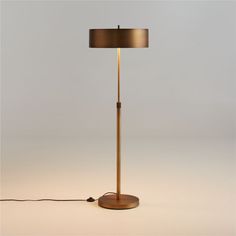 a floor lamp with a wooden base and a black shade on the top, sitting on a white surface