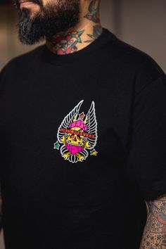 a tattooed man wearing a black t - shirt with an image of a bird on it