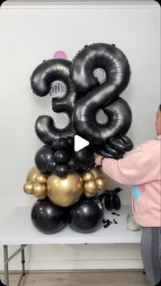 a person standing next to a large number balloon