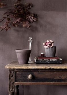 a wooden table topped with books and vases filled with flowers next to a plant