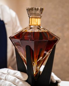 a glass bottle sitting on top of a table next to a white gloved hand