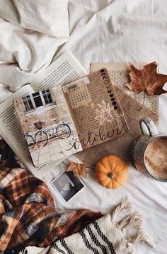 an open book, coffee cup and other items on a bed