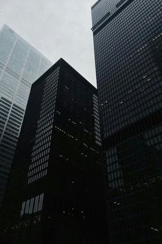 some very tall buildings in the middle of a cloudy sky area with no one around them