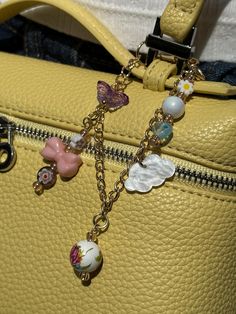 a yellow purse with charms attached to it