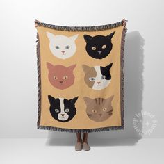 a woman holding up a tapestry with cats on it