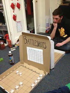 a man sitting on the floor next to a cardboard box with a game in it