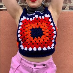 a woman wearing a crocheted crop top with an orange and blue flower on it