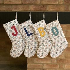 three christmas stockings hanging from a fireplace with the word noel written on them in multicolored letters