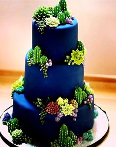 a three tiered blue cake with succulents on it