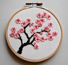 a white wall hanging with pink flowers and a black tree in the middle on it