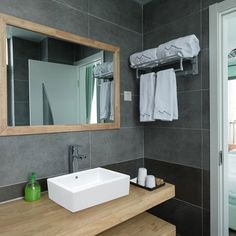 a bathroom with a sink, mirror and towels on the rack in front of it