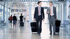 two men in suits are walking through an airport