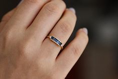 a woman's hand wearing a gold ring with blue sapphire stones on the band