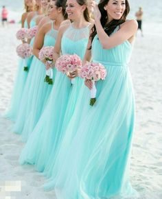 a group of women standing on top of a beach next to each other holding bouquets