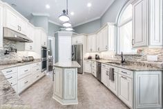 a large kitchen with marble counter tops and white cabinets