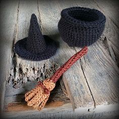 two crocheted witches hats and a broom on a wooden table with wood planks