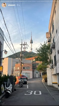 an alley way with cars parked on both sides and a building in the background that has a steeple