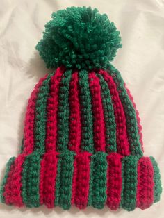 a red and green knitted hat laying on top of a bed